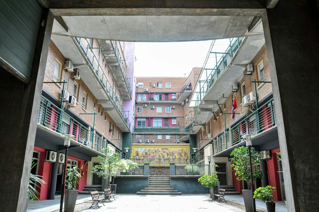 Courtyard of an apartment building with balconies and potted plants (Photo by Nikolai Kolosov on Unsplash)