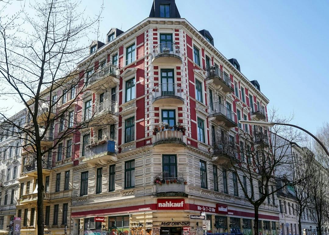 Old corner apartment building with a red and white facade in Hamburg (Photo by Wolfgang Weiser on Unsplash)