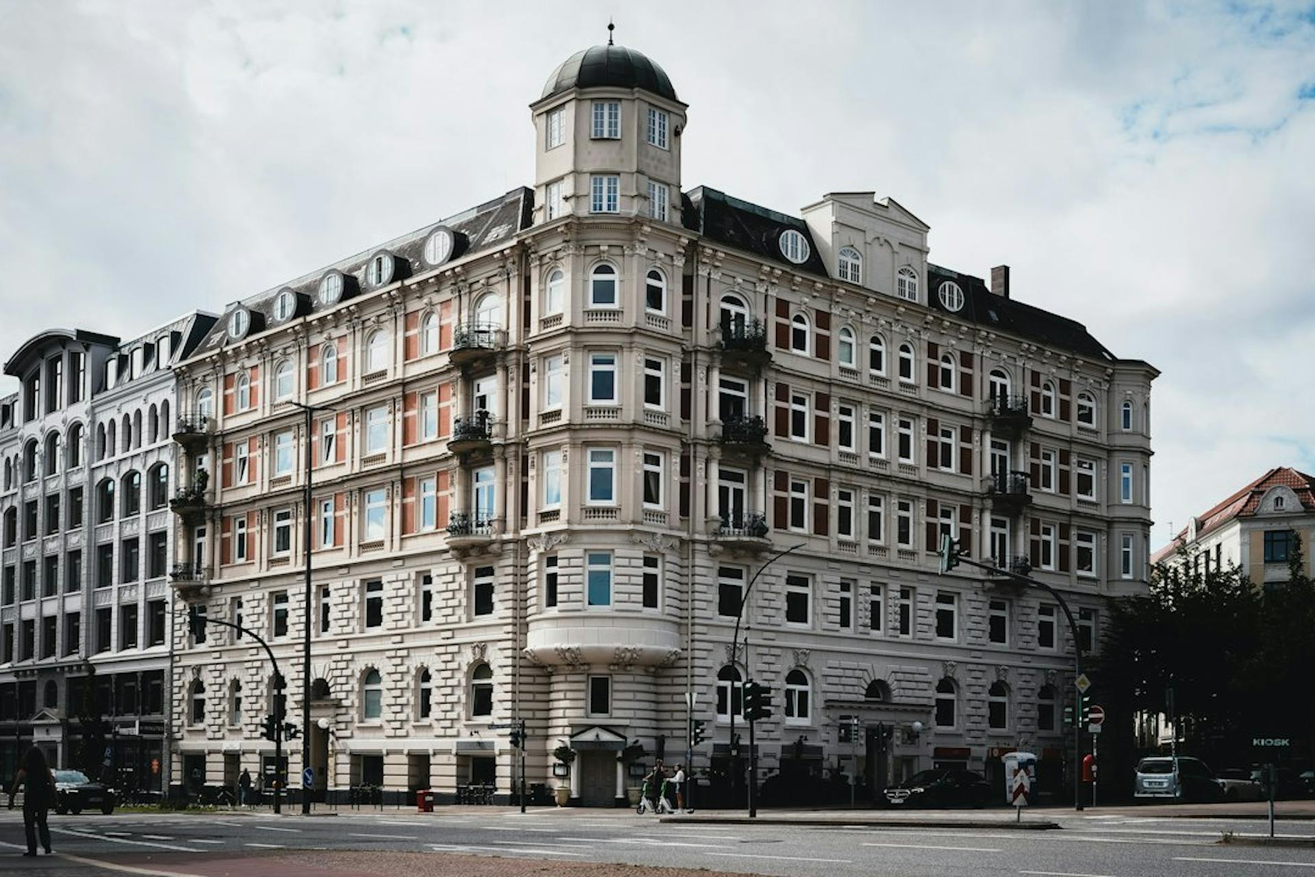 Corner apartment building with a domed tower on a street in Hamburg (Photo by Wolfgang Weiser on Unsplash)