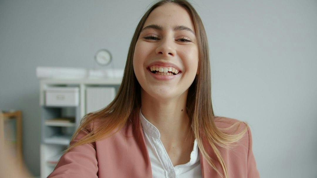 Young woman holding a passport and smartphone while opening a bank account online (Photo by Vitaly Gariev on Unsplash)