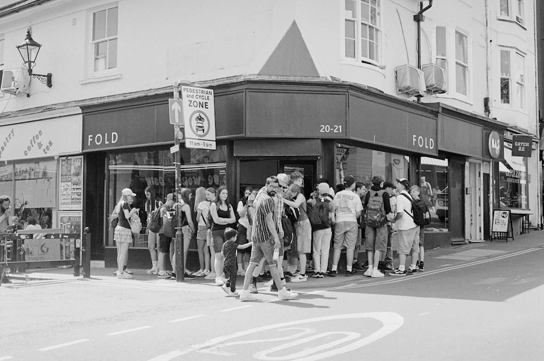 Young people standing in a queue on a city pavement (Photo by T on Unsplash)