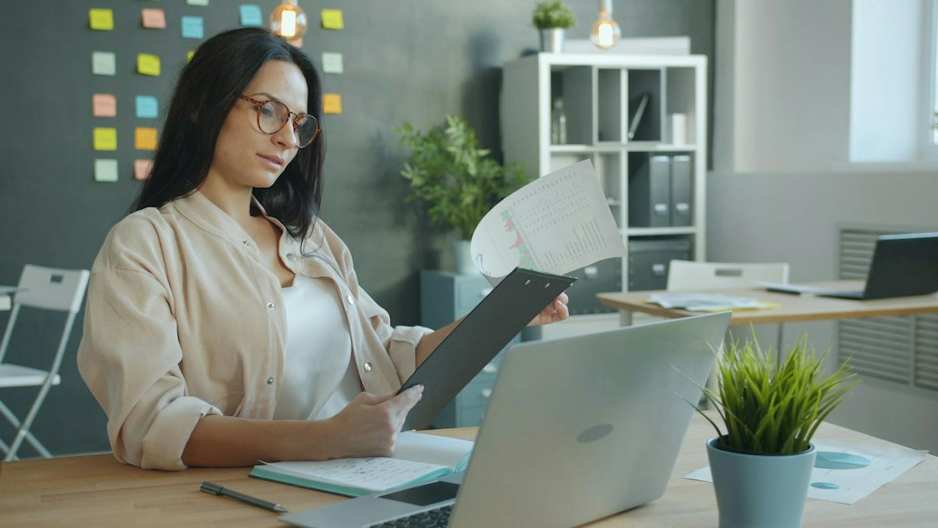 Young woman checking a utility cost statement next to her laptop at a desk (Photo by Vitaly Gariev on Unsplash)