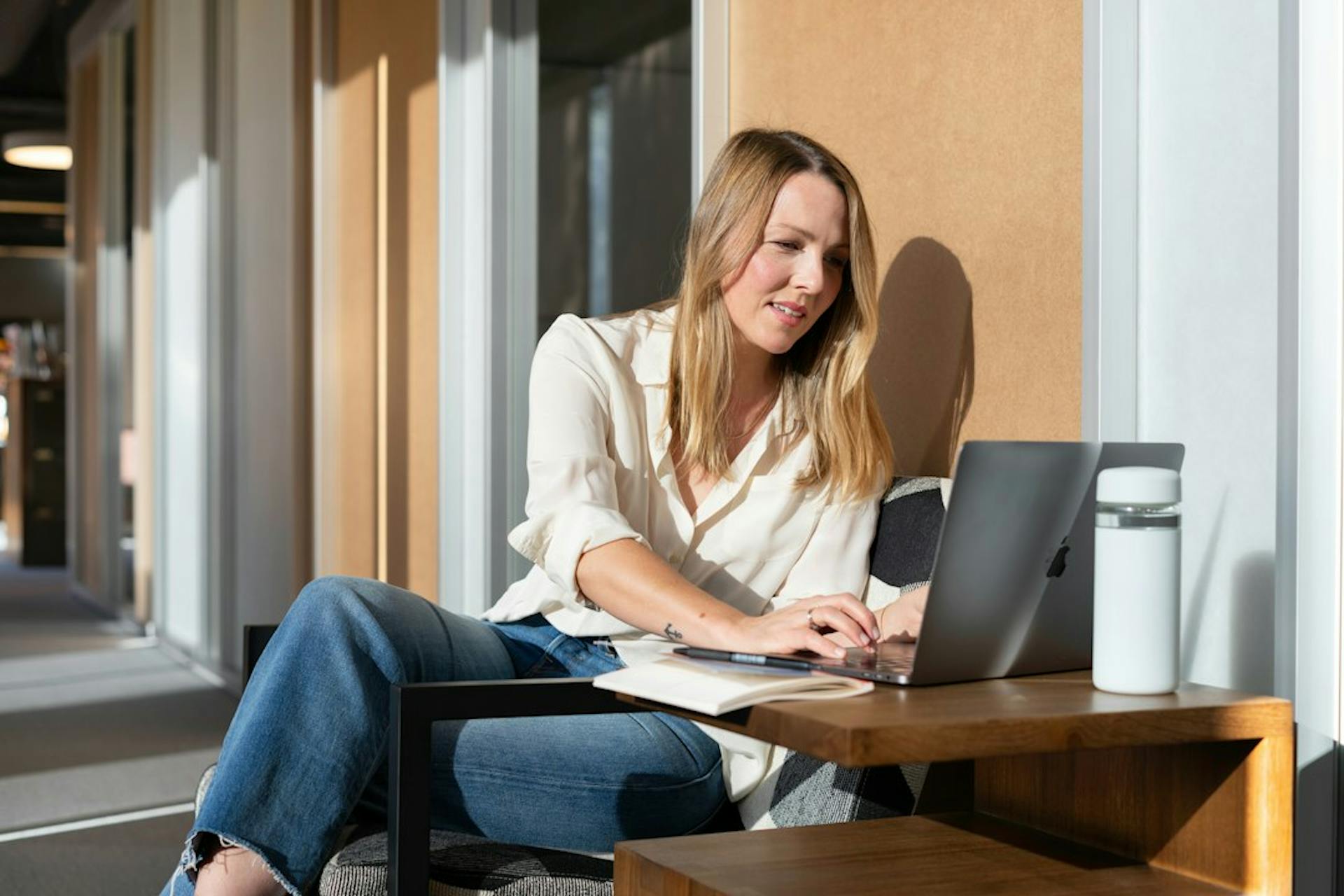 Young woman working on a laptop at a sunny table (Photo by LinkedIn Sales Solutions on Unsplash)