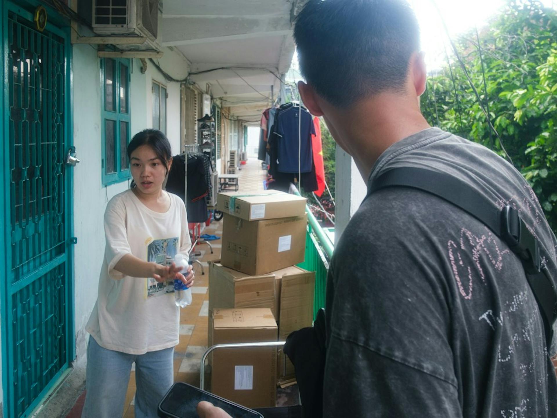 Two young people with stacked moving boxes on a balcony walkway (Photo by Tri Vo on Unsplash)