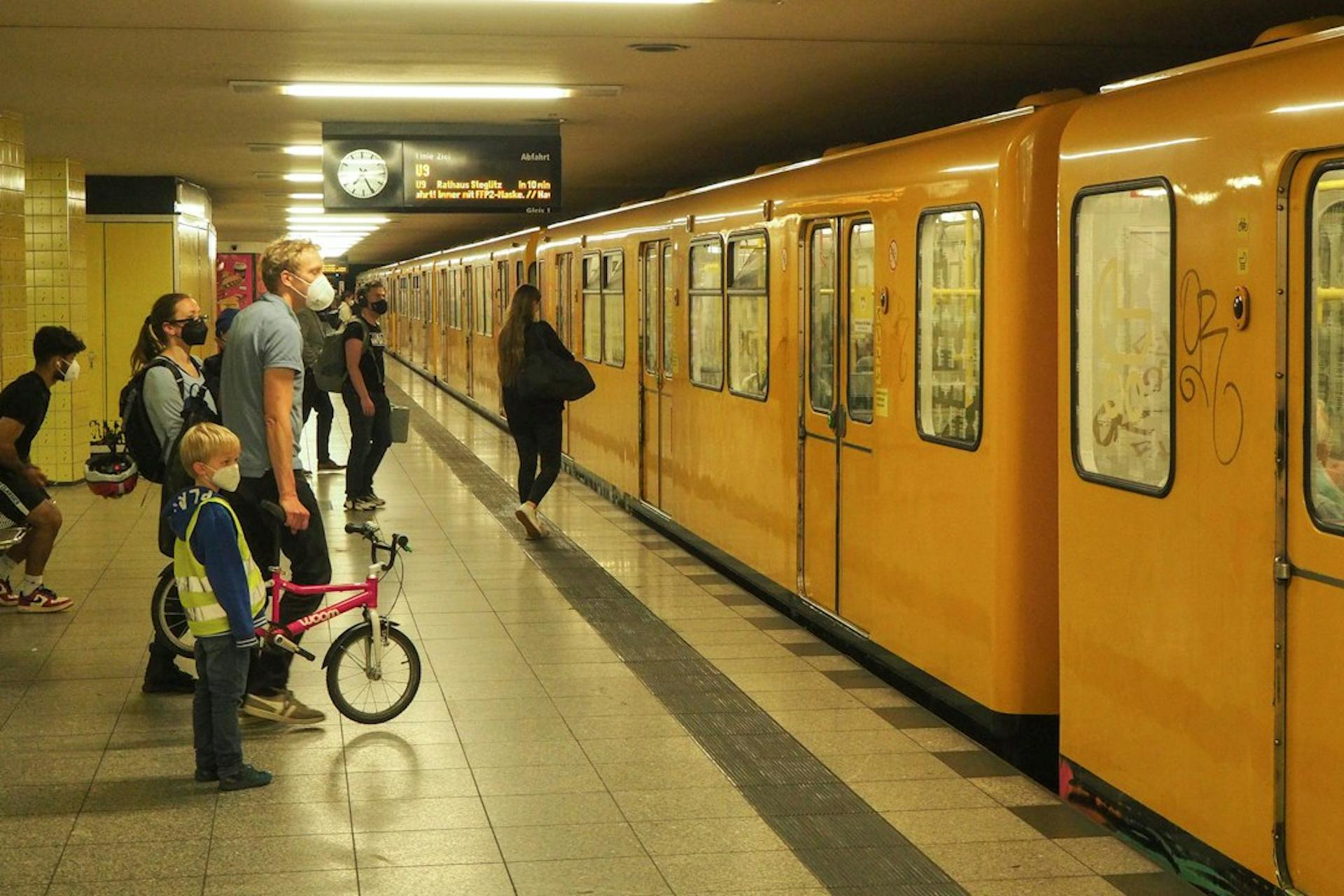Fahrgäste warten neben einer gelben U-Bahn in Berlin (Photo by Lawrence Chismorie on Unsplash)