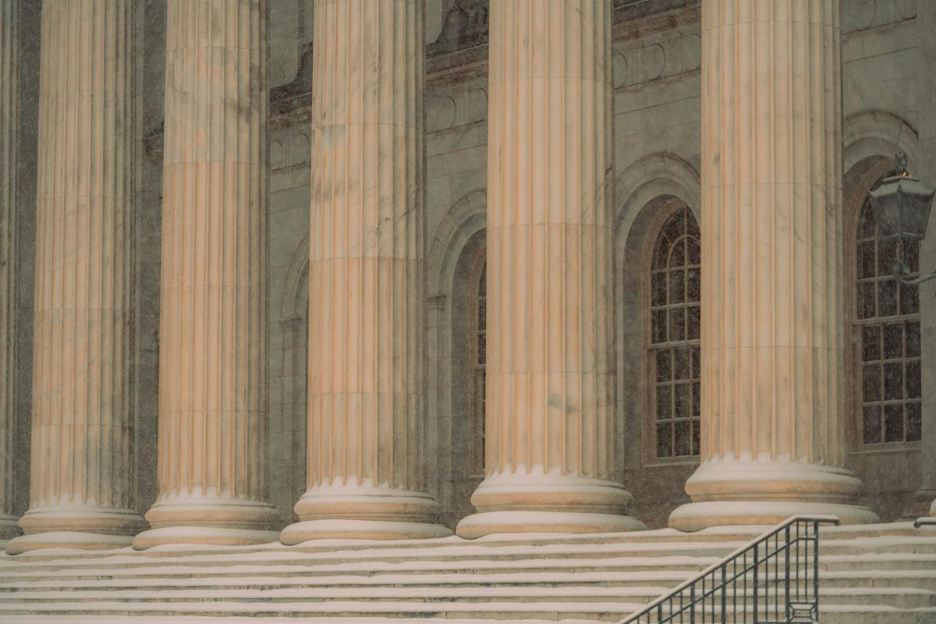 Stone columns at the entrance of a classical courthouse building (Photo by Colin Lloyd on Unsplash)