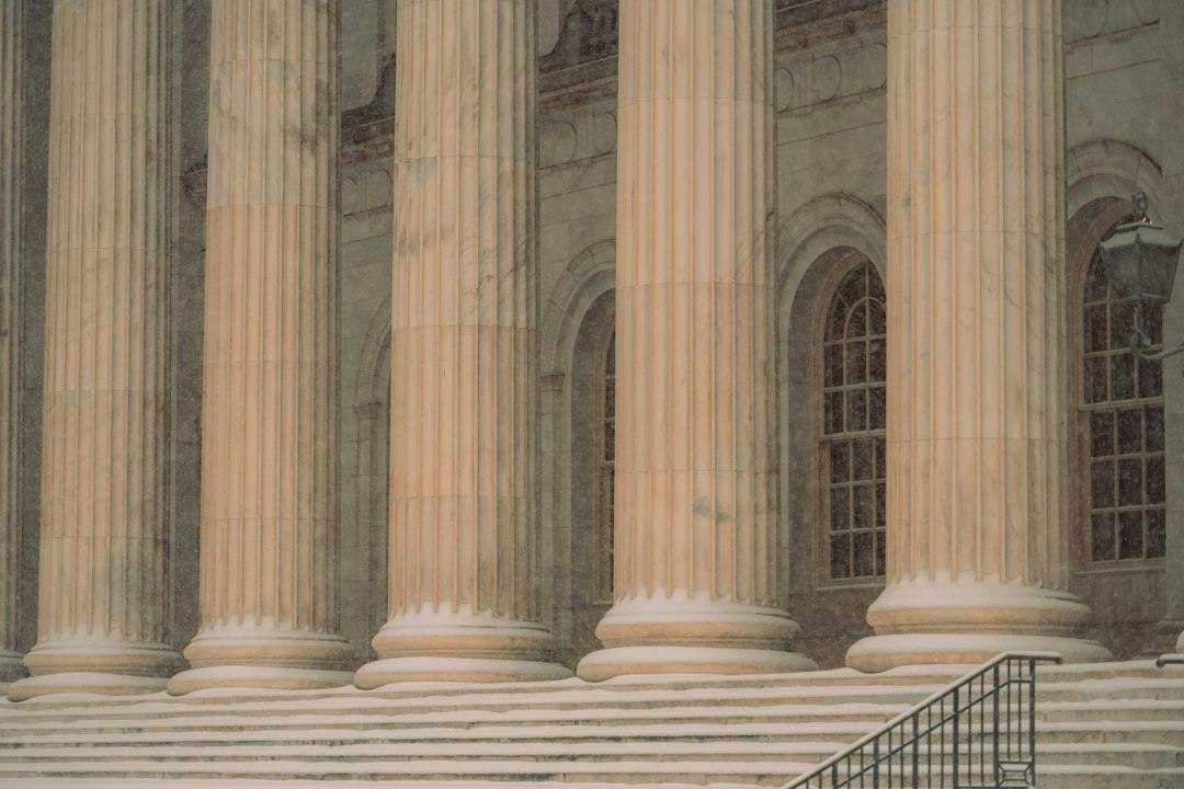 Stone columns at the entrance of a classical courthouse building (Photo by Colin Lloyd on Unsplash)