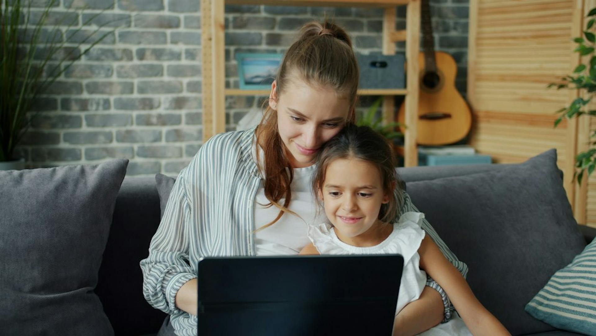 Woman and girl looking at a laptop on a sofa (Photo by Vitaly Gariev on Unsplash)