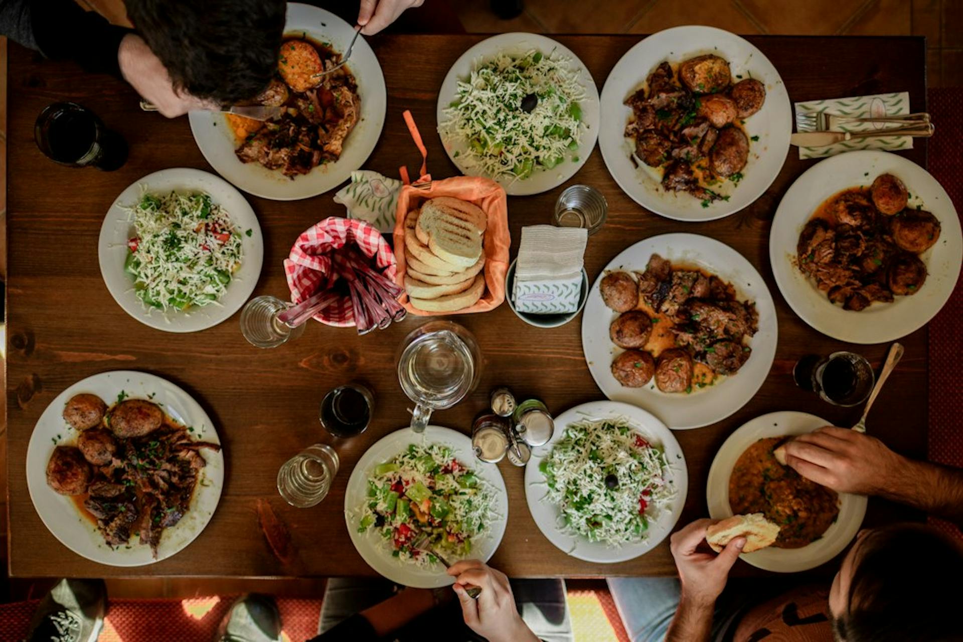 Many plates of food shared on a long table seen from above (Photo by Stefan Vladimirov on Unsplash)