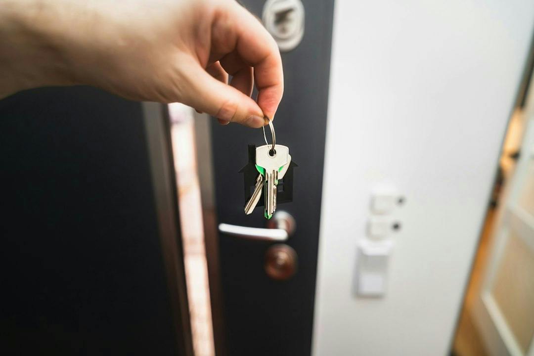 Hand hanging a key in the lock of an apartment door (Photo by Jakub Żerdzicki on Unsplash)