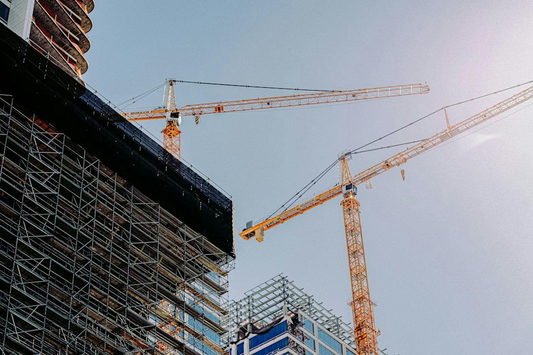 Cranes and scaffolding at a new residential construction site (Photo by Frames For Your Heart on Unsplash)