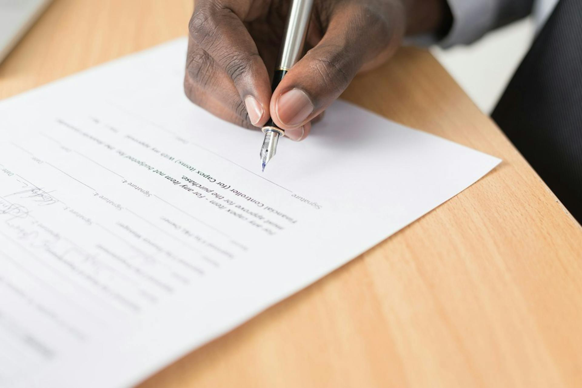 Hand signing a document with a fountain pen (Photo by Cytonn Photography on Unsplash)