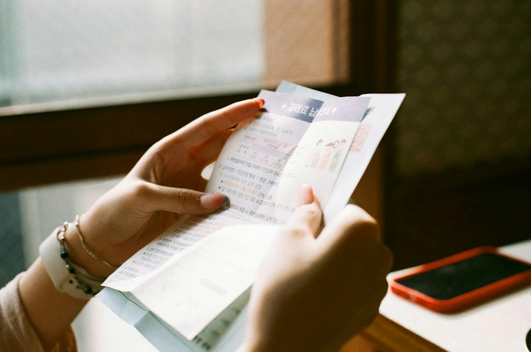 Hænder holder et udfoldet brev ved siden af en mobil (Photo by Chanhee Lee on Unsplash)
