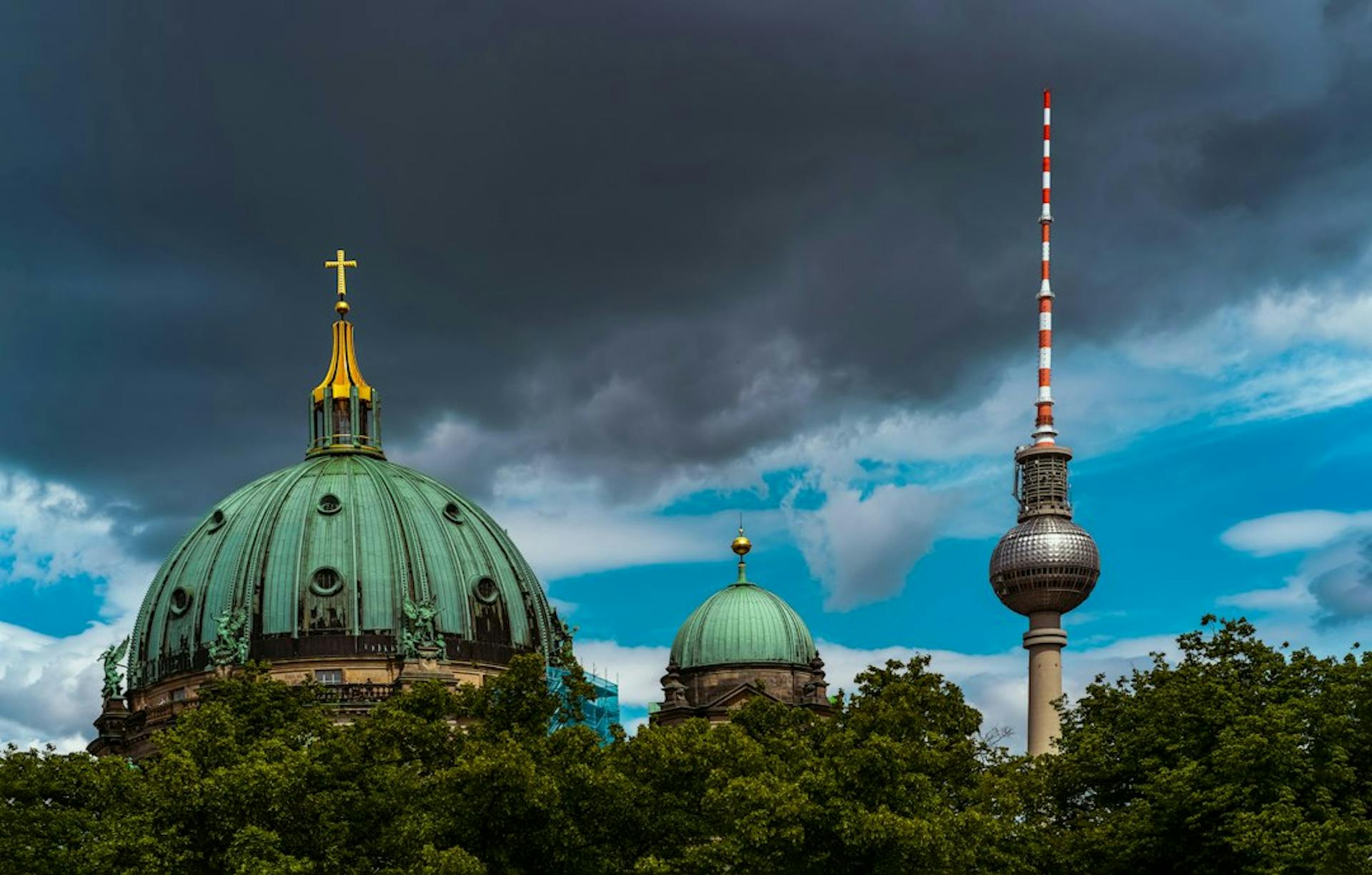 Berlin Cathedral and the TV tower under dramatic clouds (Photo by Jahanzeb Ahsan on Unsplash)