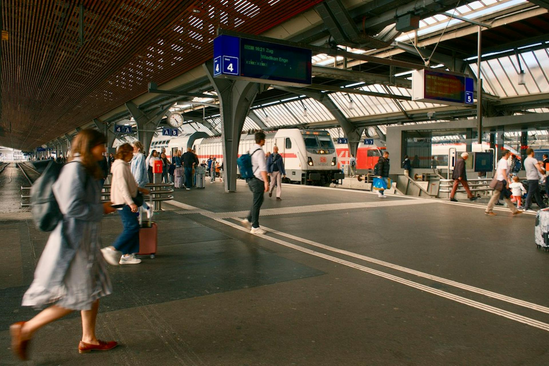 Travellers walking along a busy train station platform (Photo by Bryan Dijkhuizen on Unsplash)