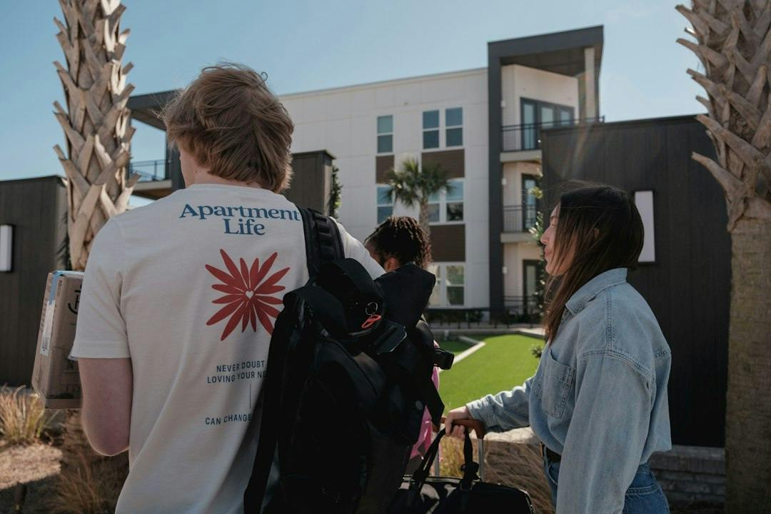 Young people walking towards modern apartment buildings (Photo by Apartment Life on Unsplash)