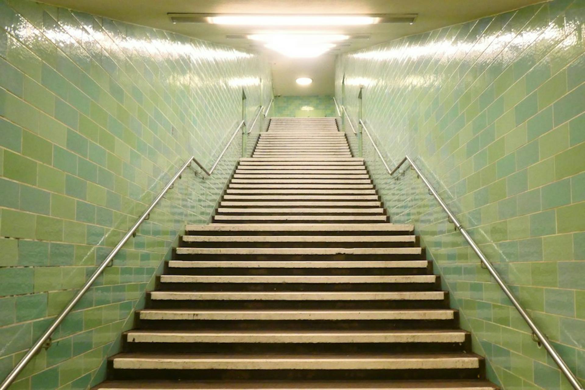 Long staircase in a green tiled underground station (Photo by Bekky Bekks on Unsplash)