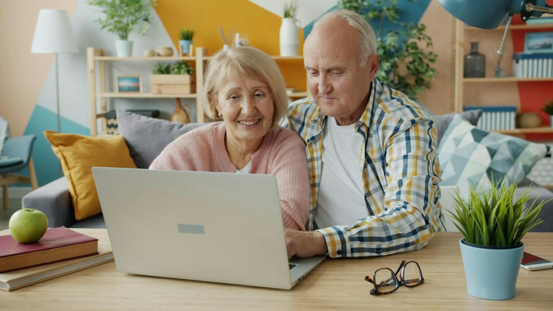 Older couple using a laptop together at a table in their living room (Photo by Vitaly Gariev on Unsplash)