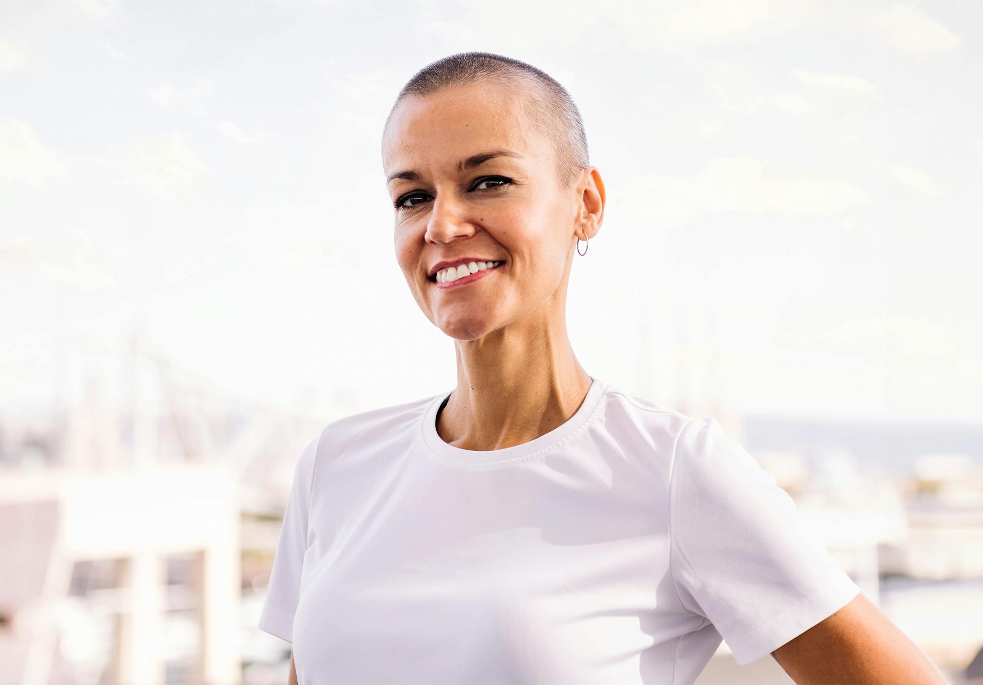 woman in a white top wearing a breast cancer awareness ribbon