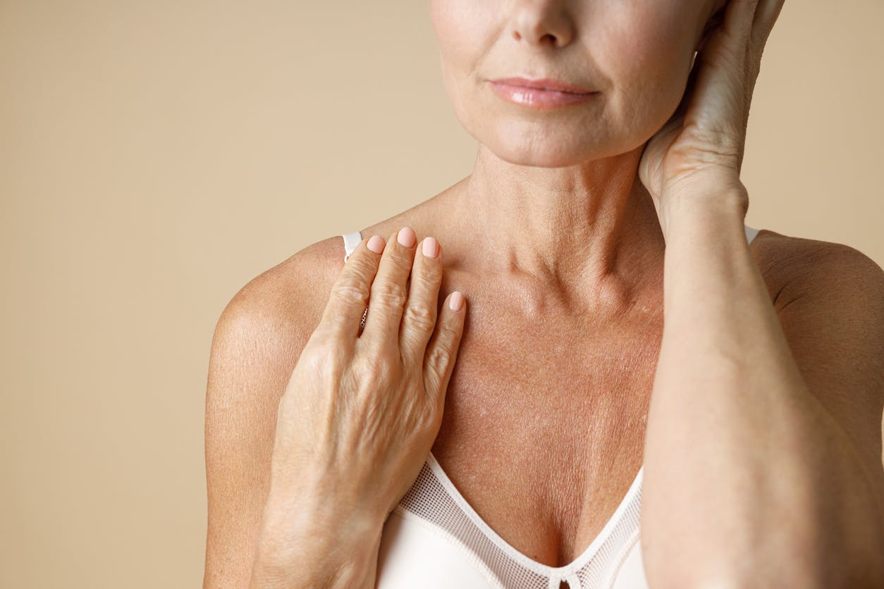 Older woman in bra touching her neck