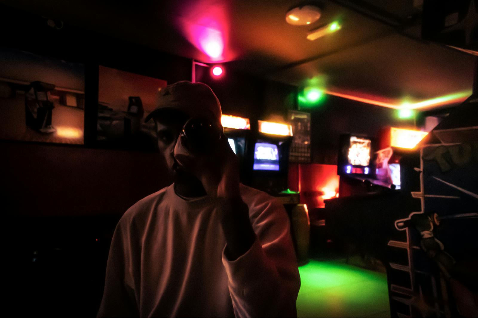 Zamaskiran mlad moški v igralnici, v ozadju igralni aparati.