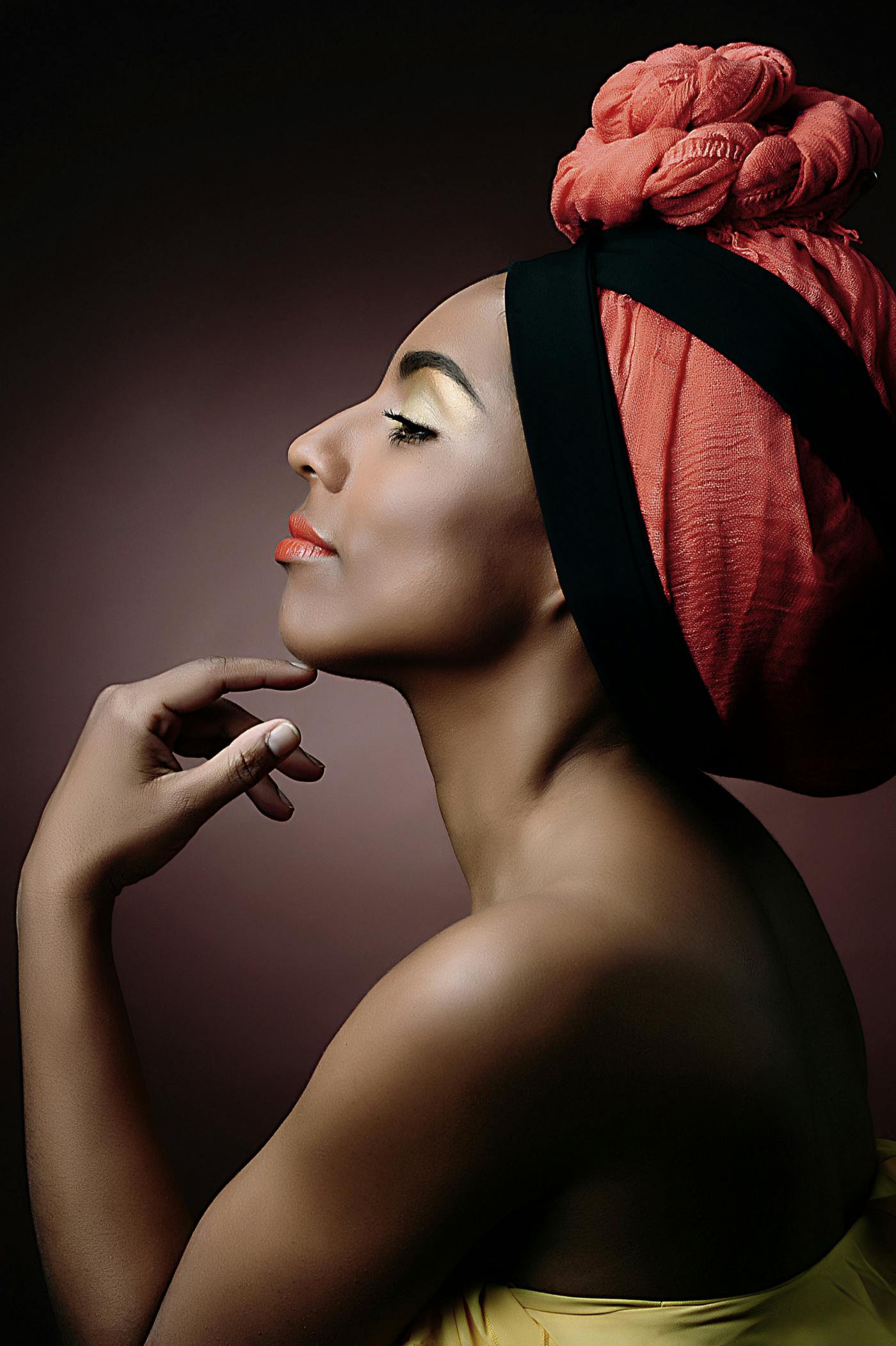 Portret intervjuvanke od strani, na glavi ima zavito rdečo ruto, brado ima rahlo naslonjeno na roko