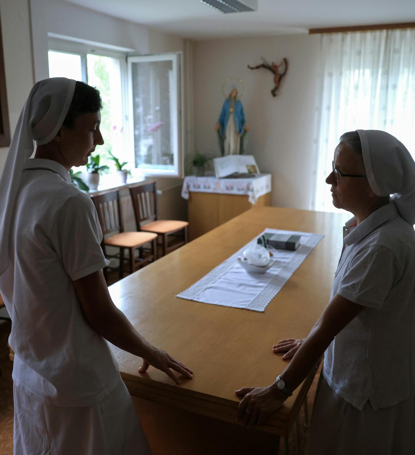 Dve redovnici stojita za mizo in se pogovarjata