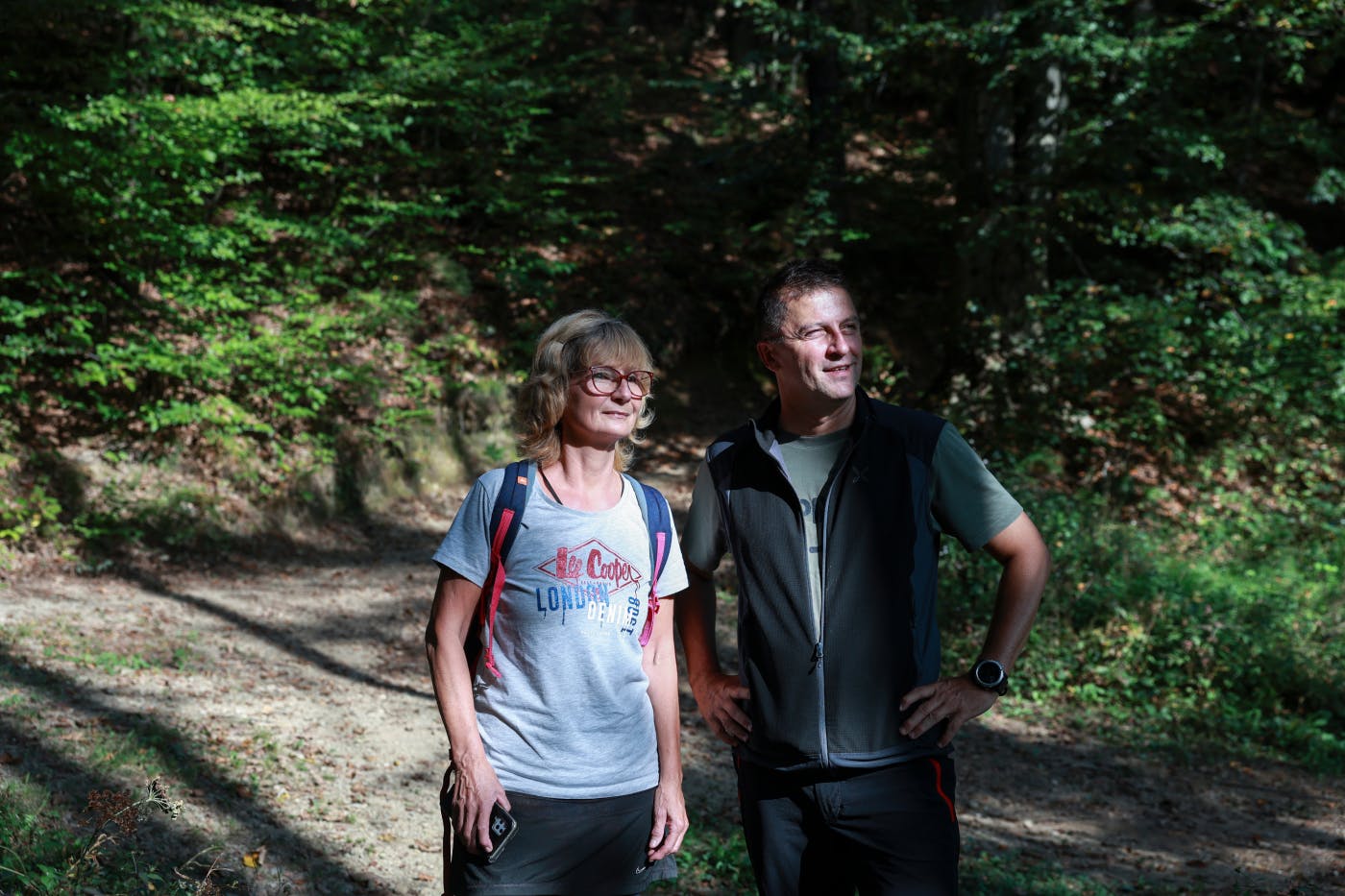 Ženska in moški stojita na pohodniški poti v gozdu