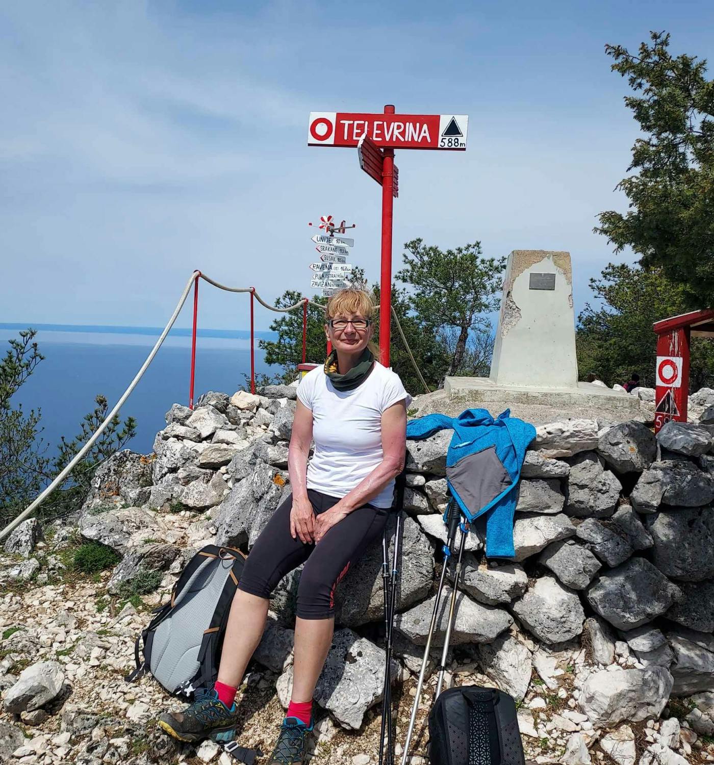 Ženska sloni na kamnitem zidku na vrhu gore