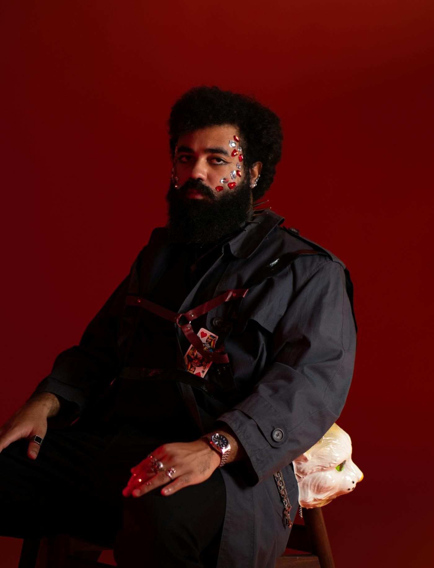 Studijska fotografija Tschimyja na rdečem ozadju, na obrazu ima večje bleščice