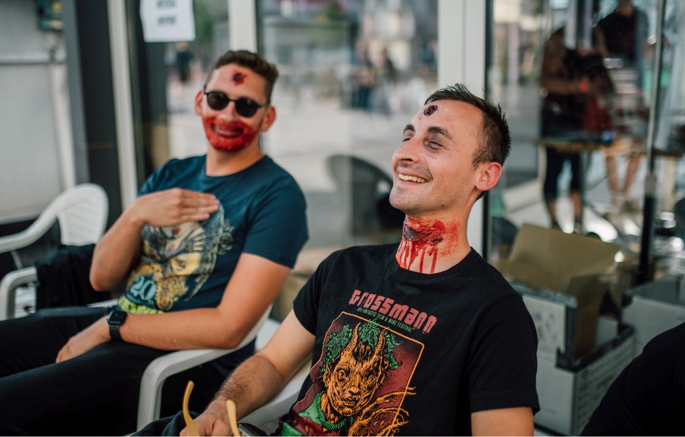 Dva moška s festivalskimi majicami, na sebi imata umetno kri