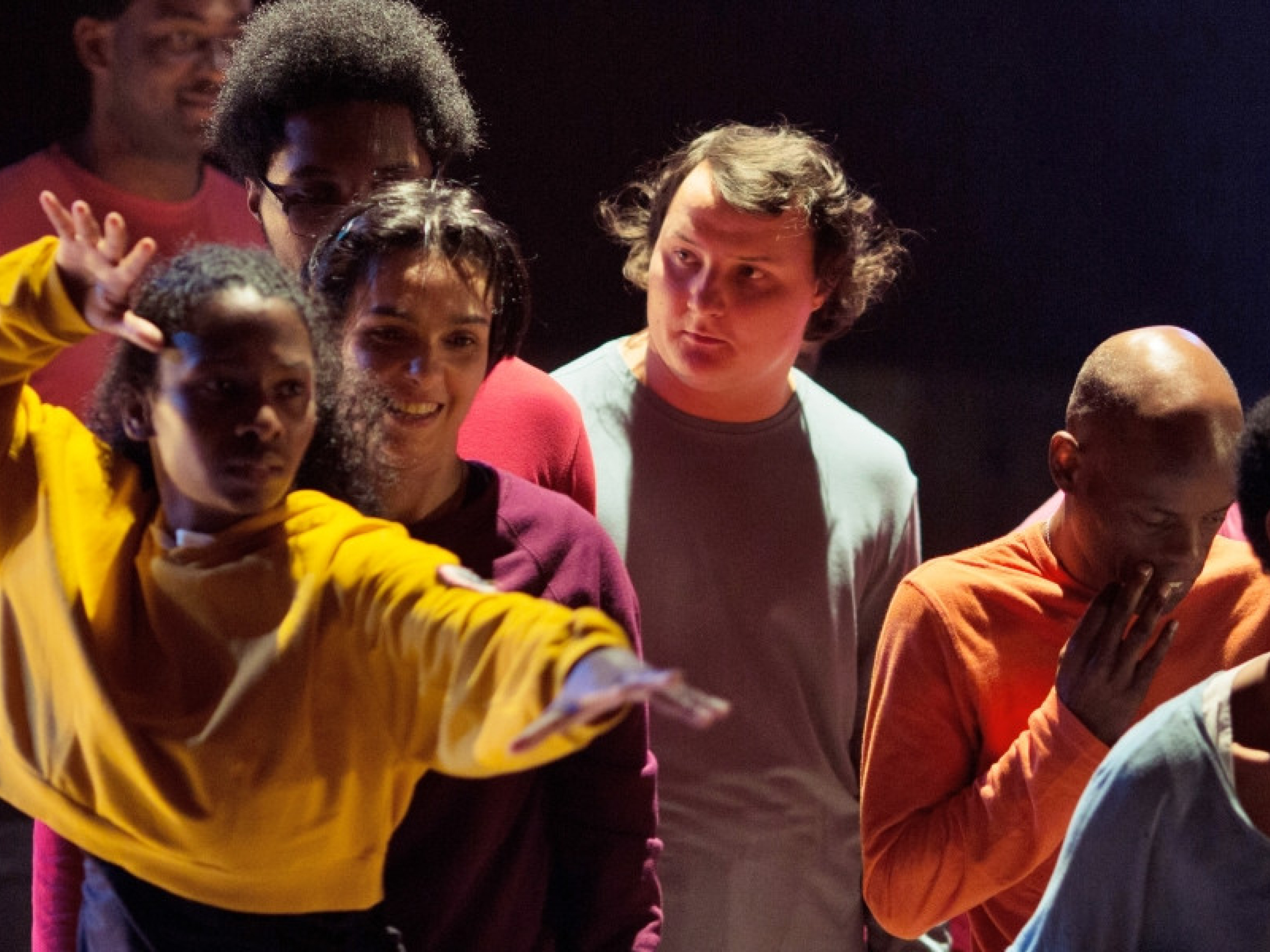 Mladi v živobarvnih oblačilih plešejo na odru.