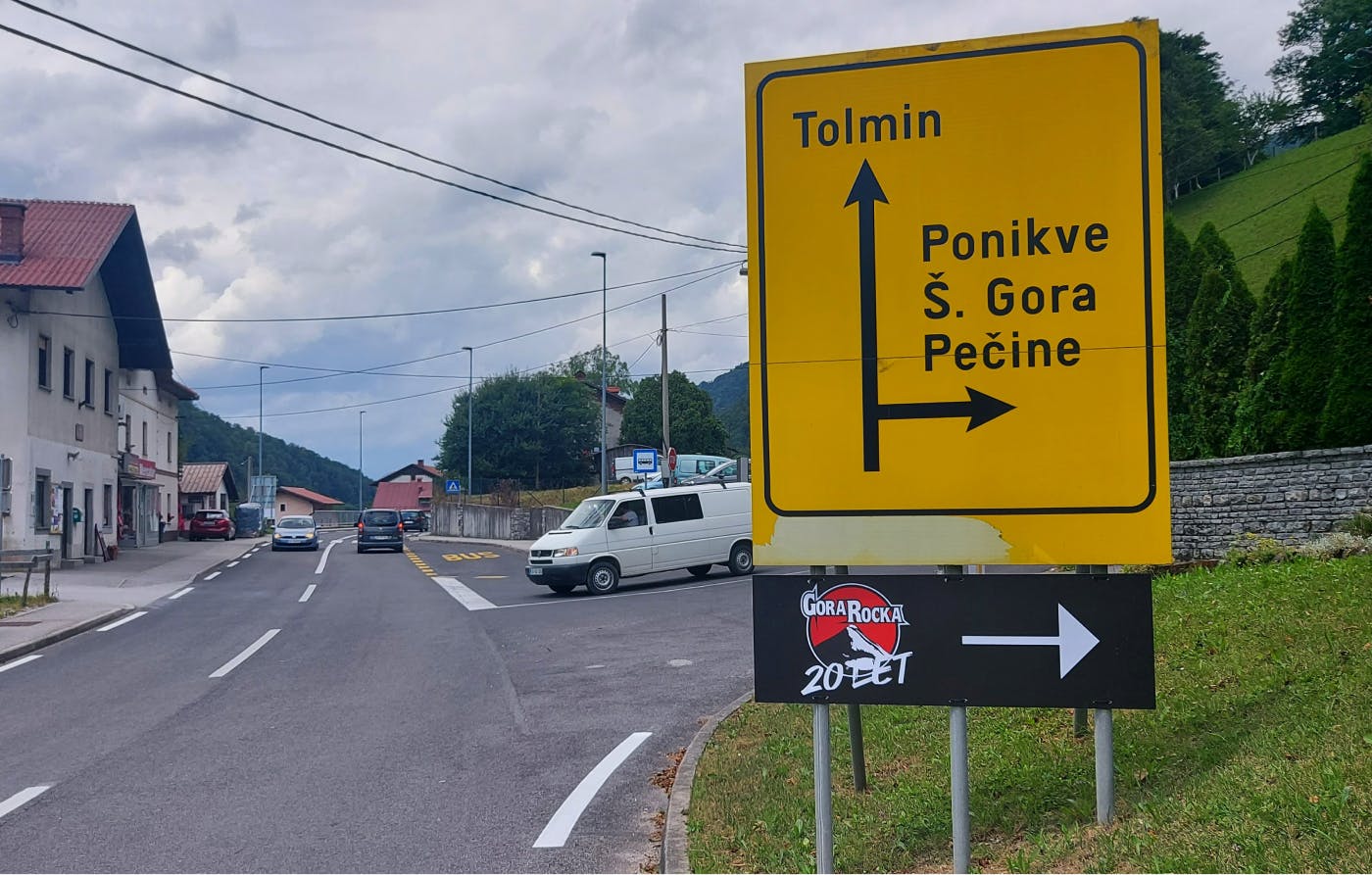 Cestna tabla, pod katero je smerokaz za festival Gora Rocka