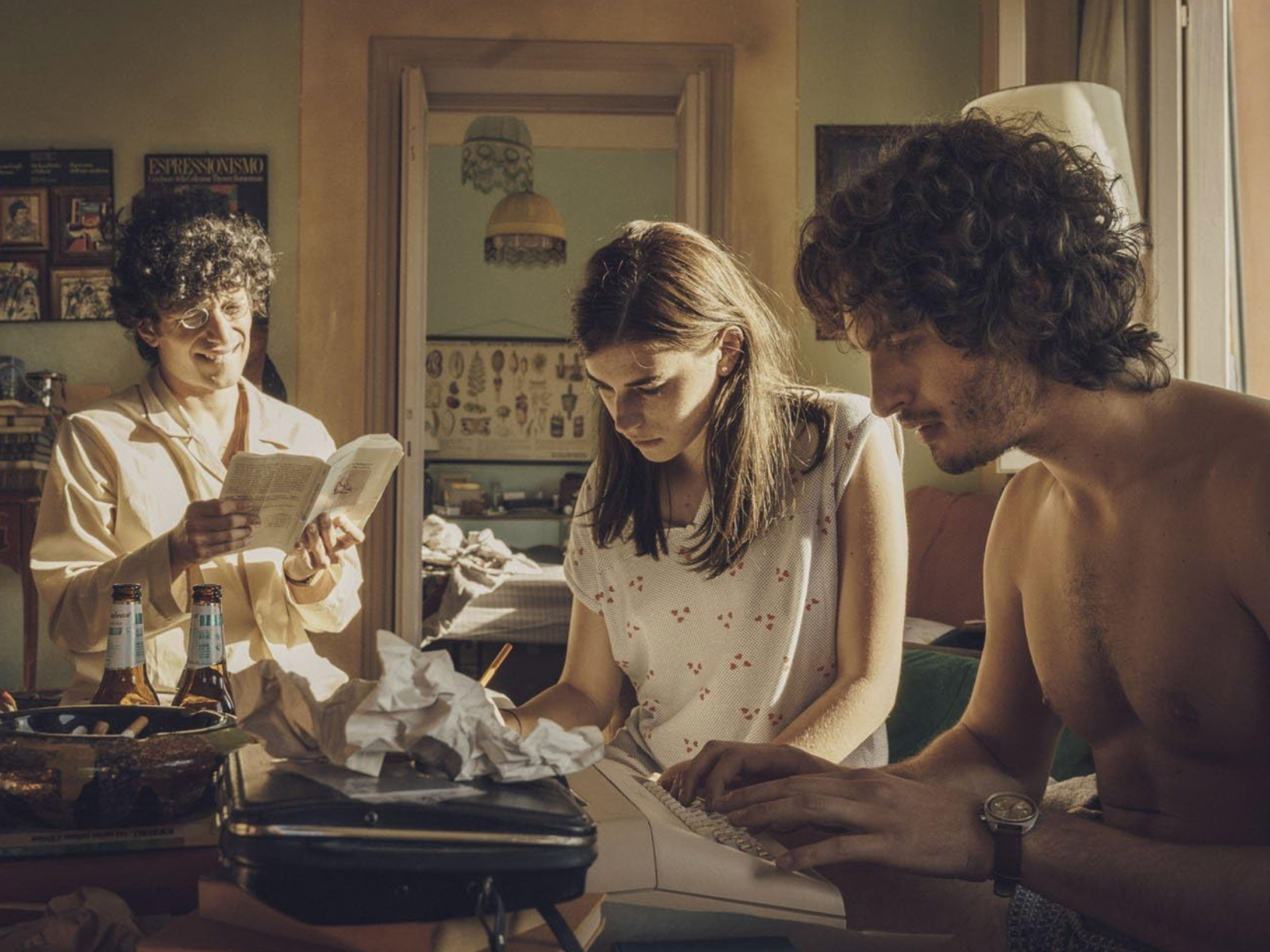 Dva fanta in med njima dekle, sedijo okrog mize in pišejo, berejo in tipkajo. Kader iz filma Čarobne noči.