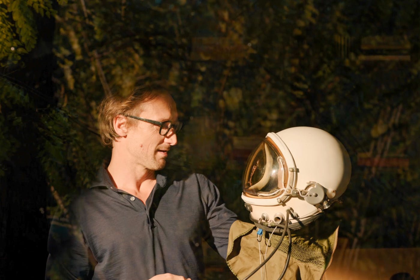 Kader iz filma, Marko Mandić v rokah drži in gleda vesoljsko masko