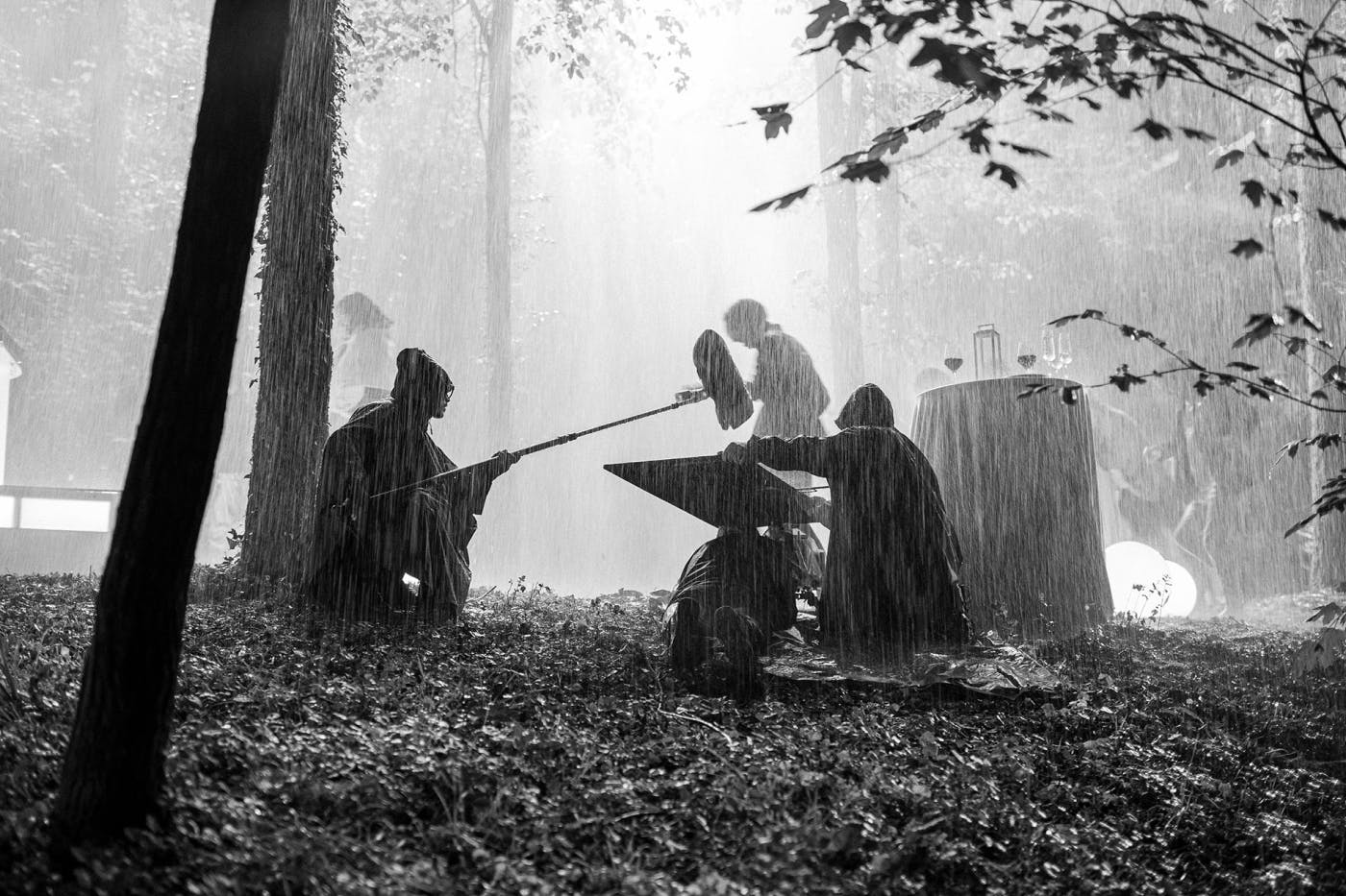 Črno-bela fotografija zakulisja snemanja filma med močnim dežjem