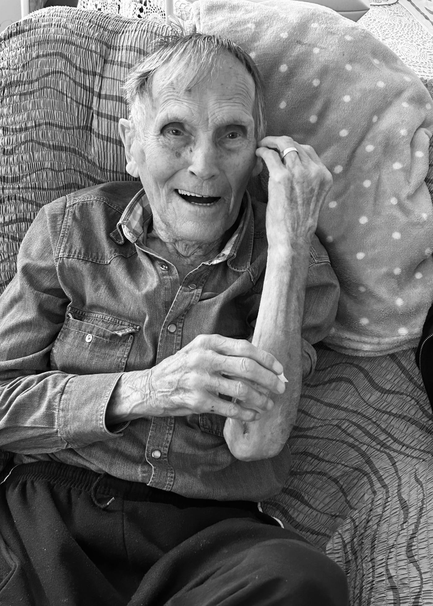 Portret dedka avtorja prispevka, sedi na fotelju in se smehlja v kamero