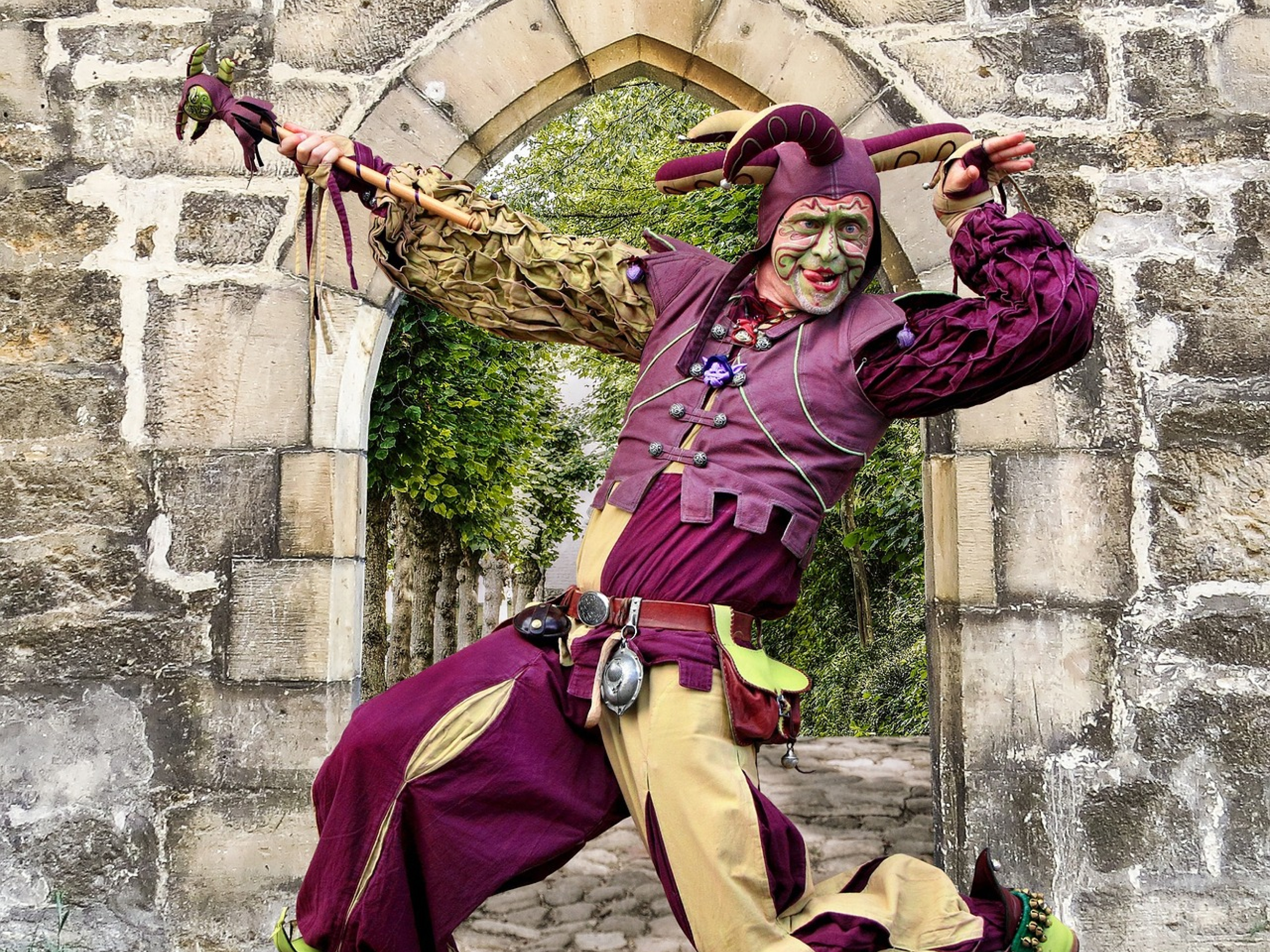 Moški v srednjeveškem kostimu dvornega norčka gleda proti nam