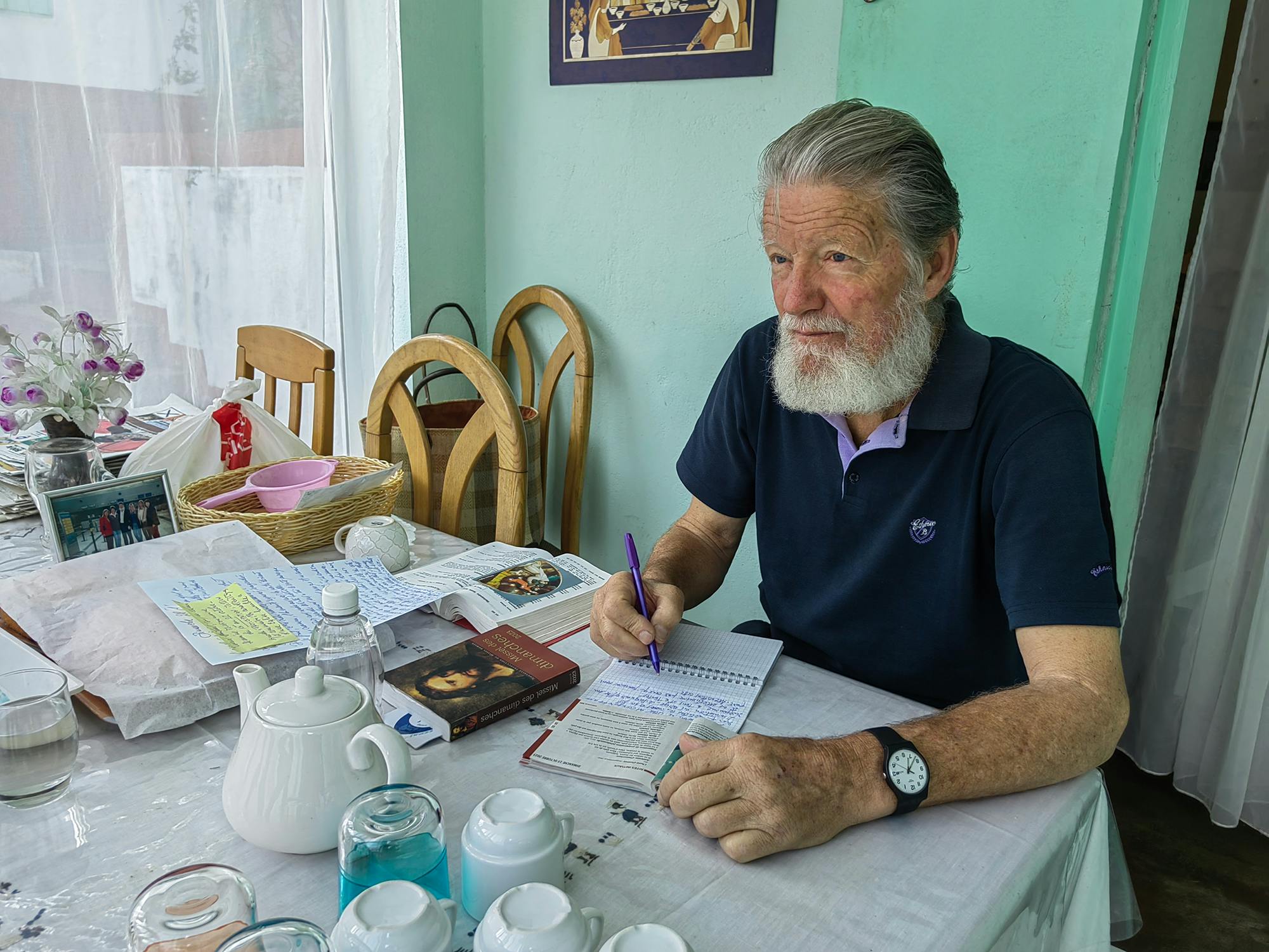 Pedro Opeka sedi za mizo in piše v beležko