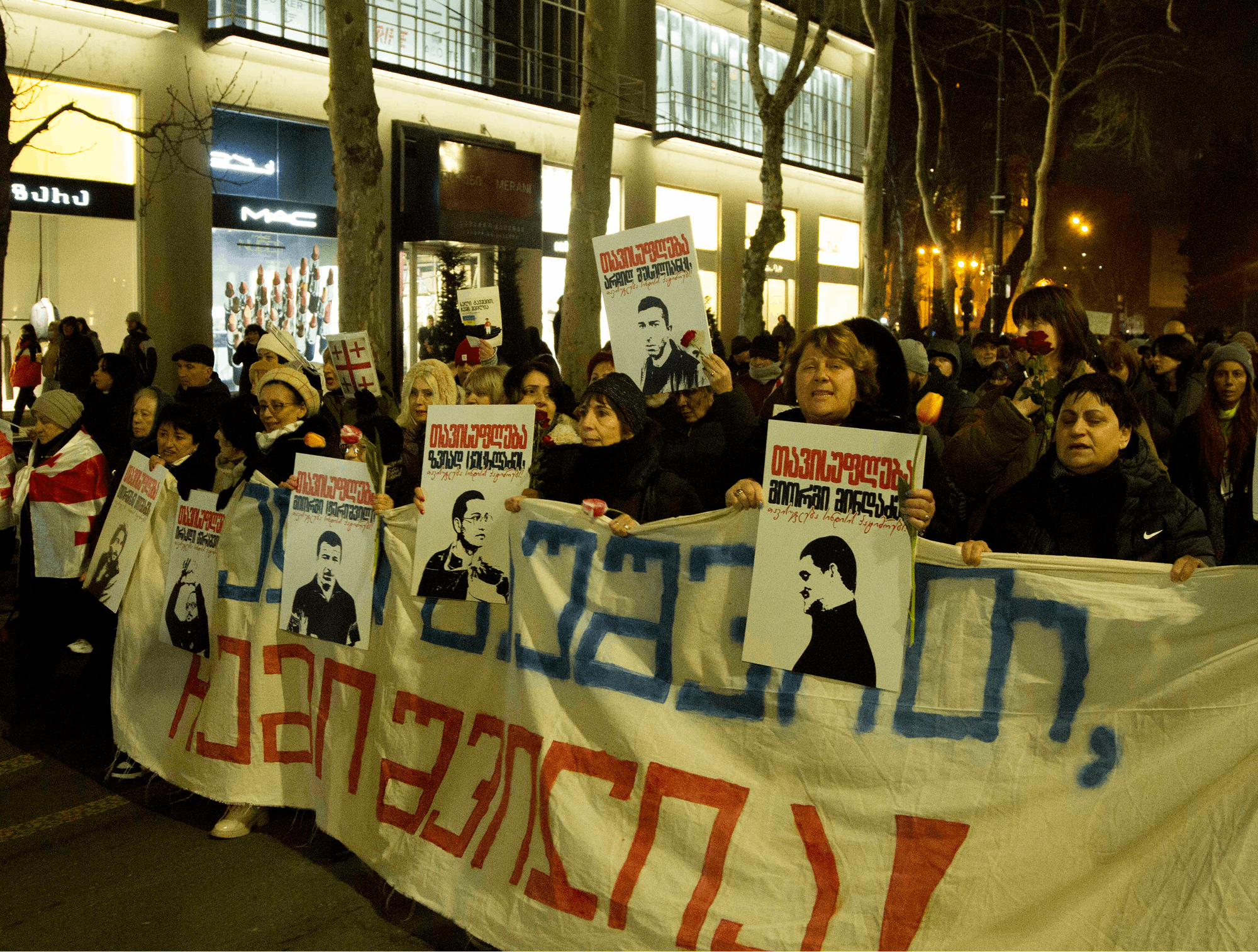 Protestniki prve vrsti s političnimi transparenti v rokah