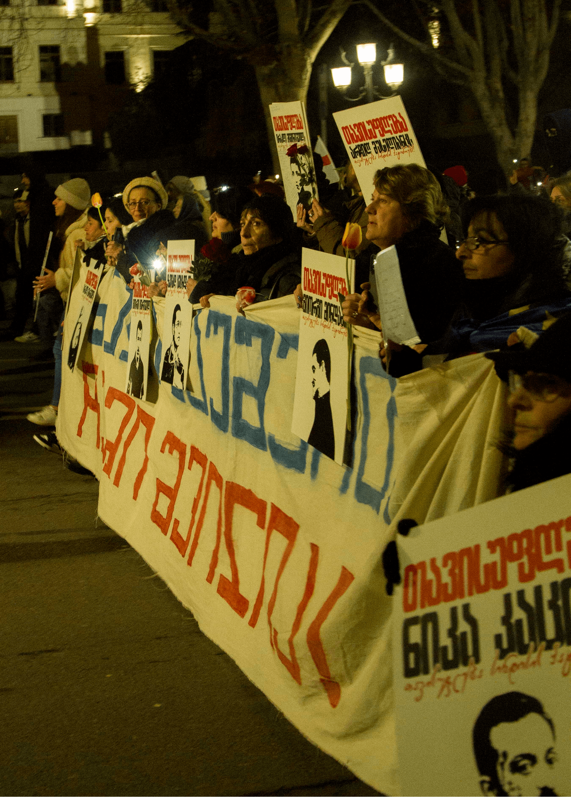 Protestniki prve vrsti s političnimi transparenti v rokah
