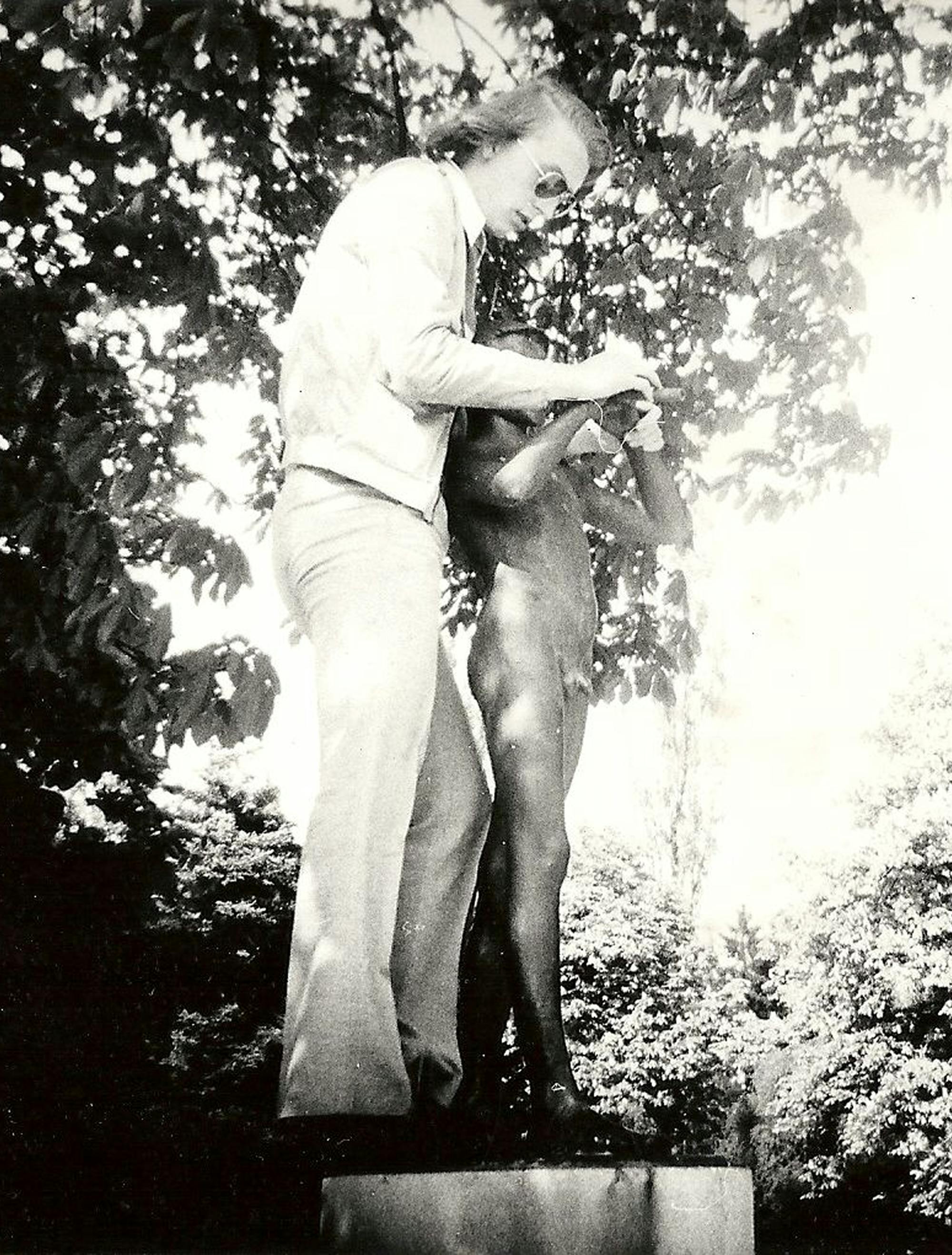 Stara črno-bela fotografija moškega ob kipu