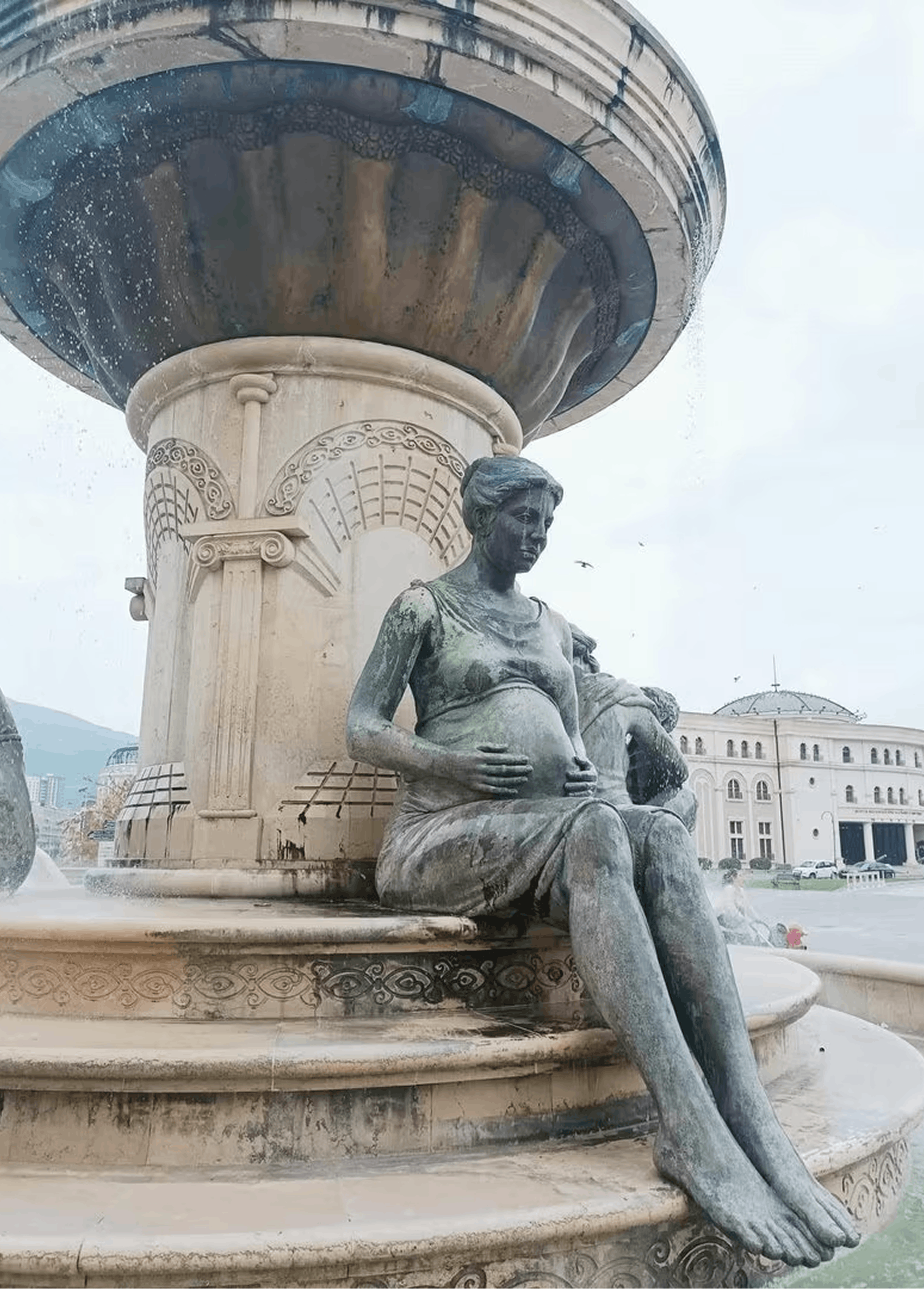 Kip noseče ženske pod fontano