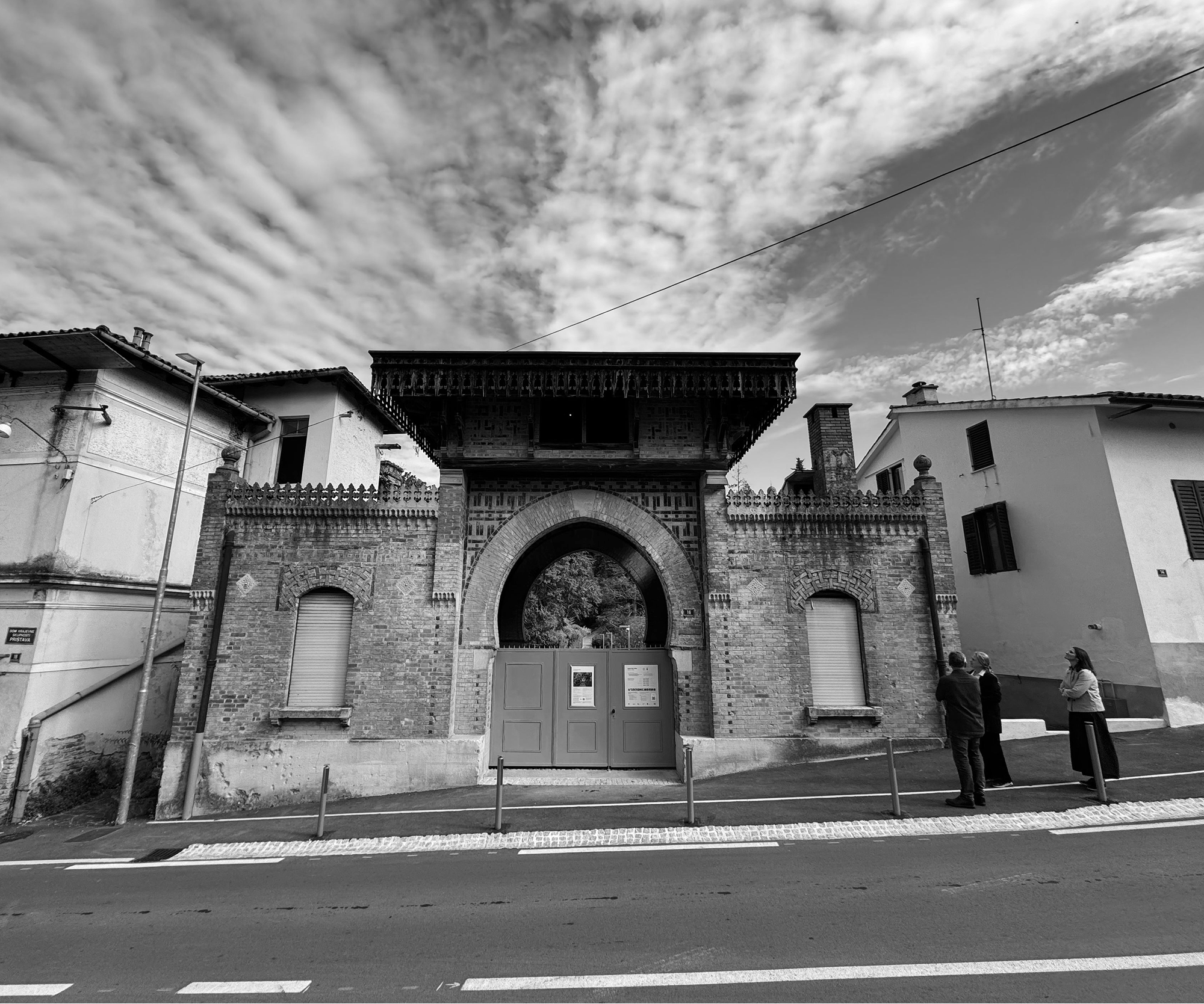 Črno-bela fotografija starejše stavbe ob cesti