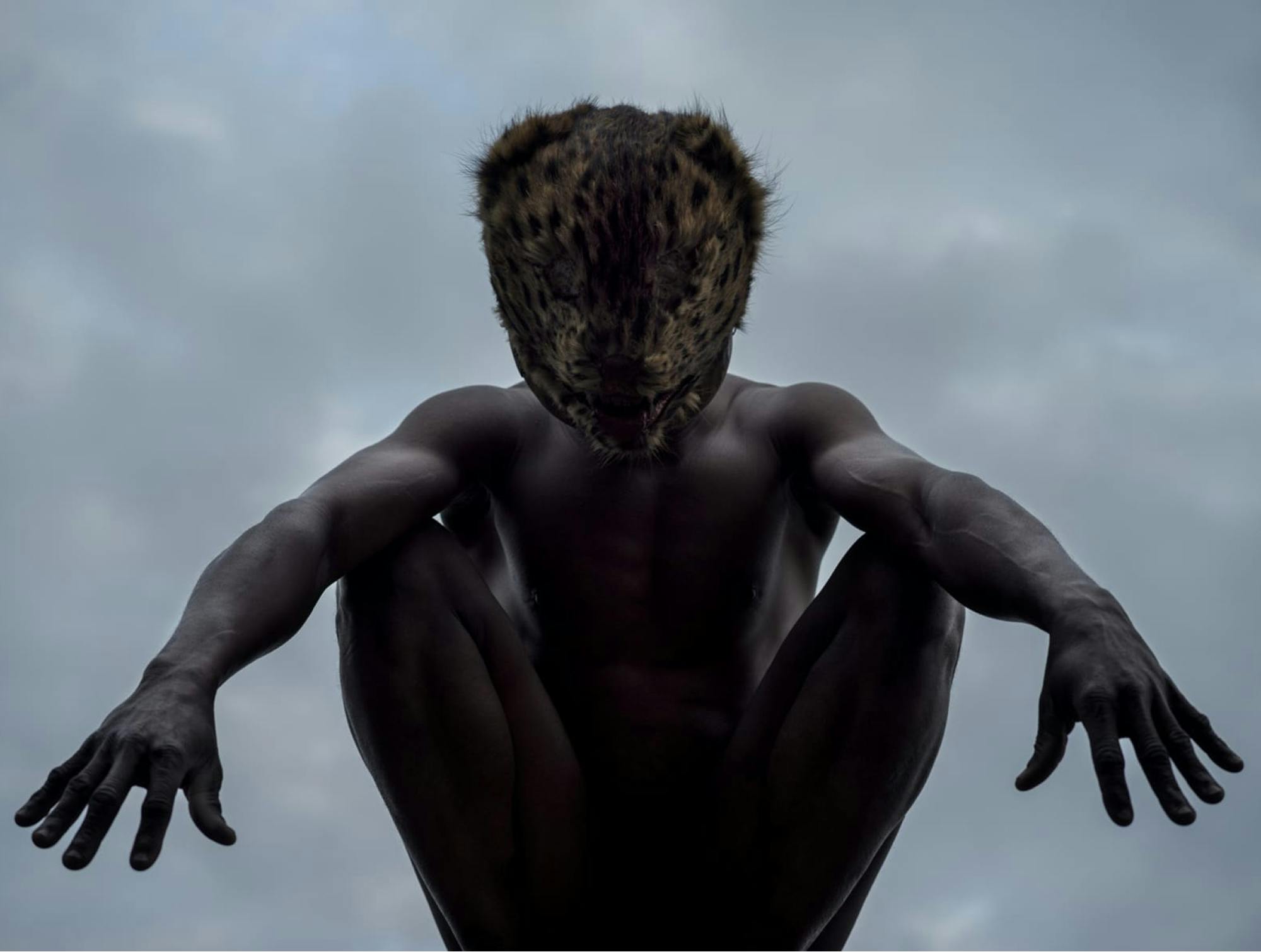 Fotografija moškega z živalsko masko, v ozadju je oblačno nebo