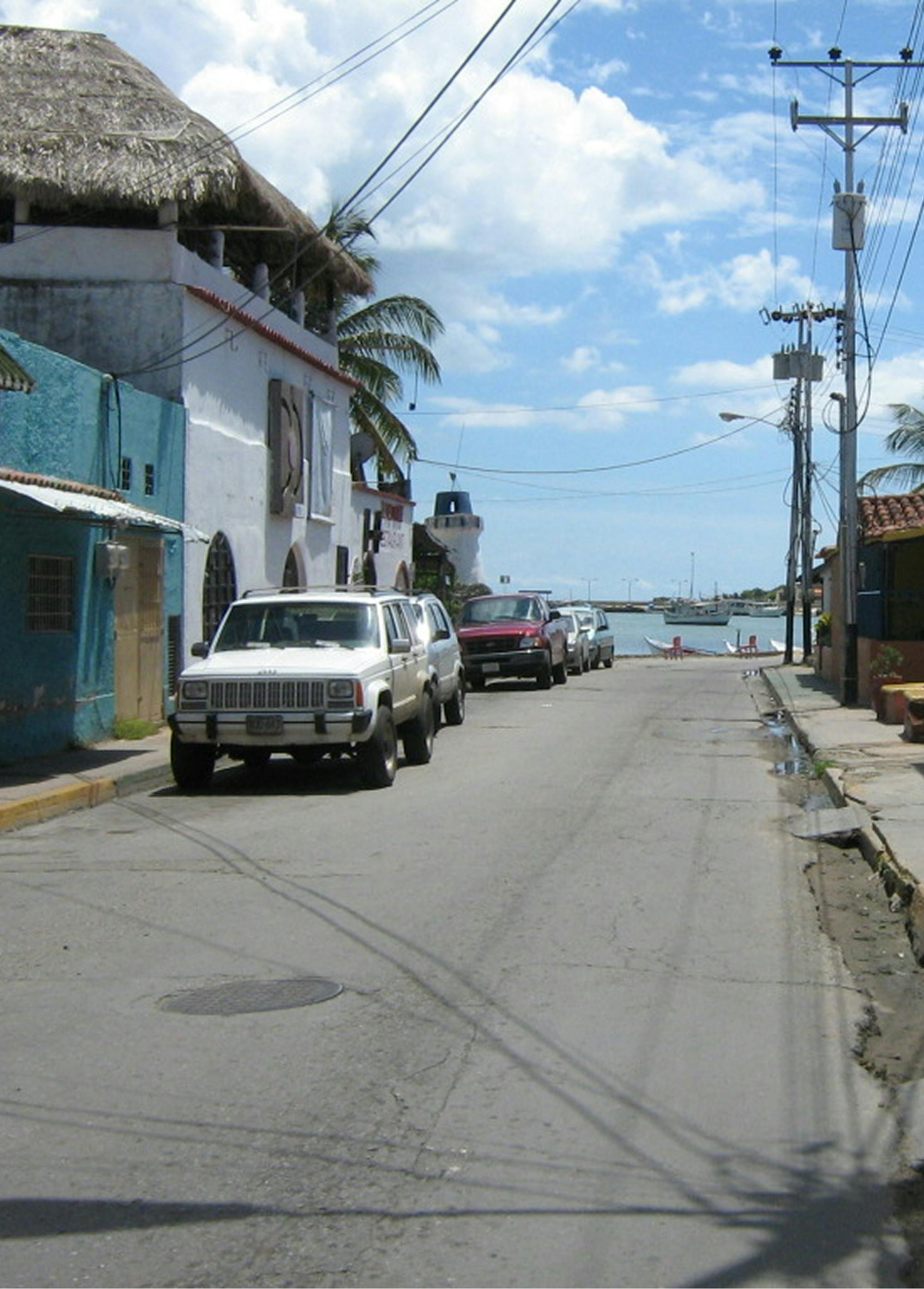 Avti parkirani na ulici in pristanišče v ozadju