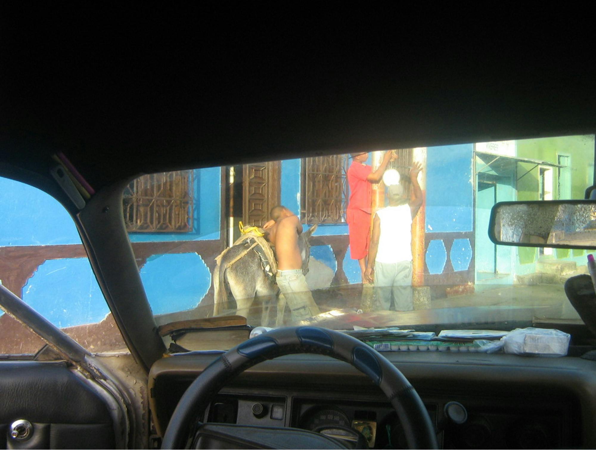 Pogled iz avtomobila na ulico, kjer ljudje nekaj popravljajo