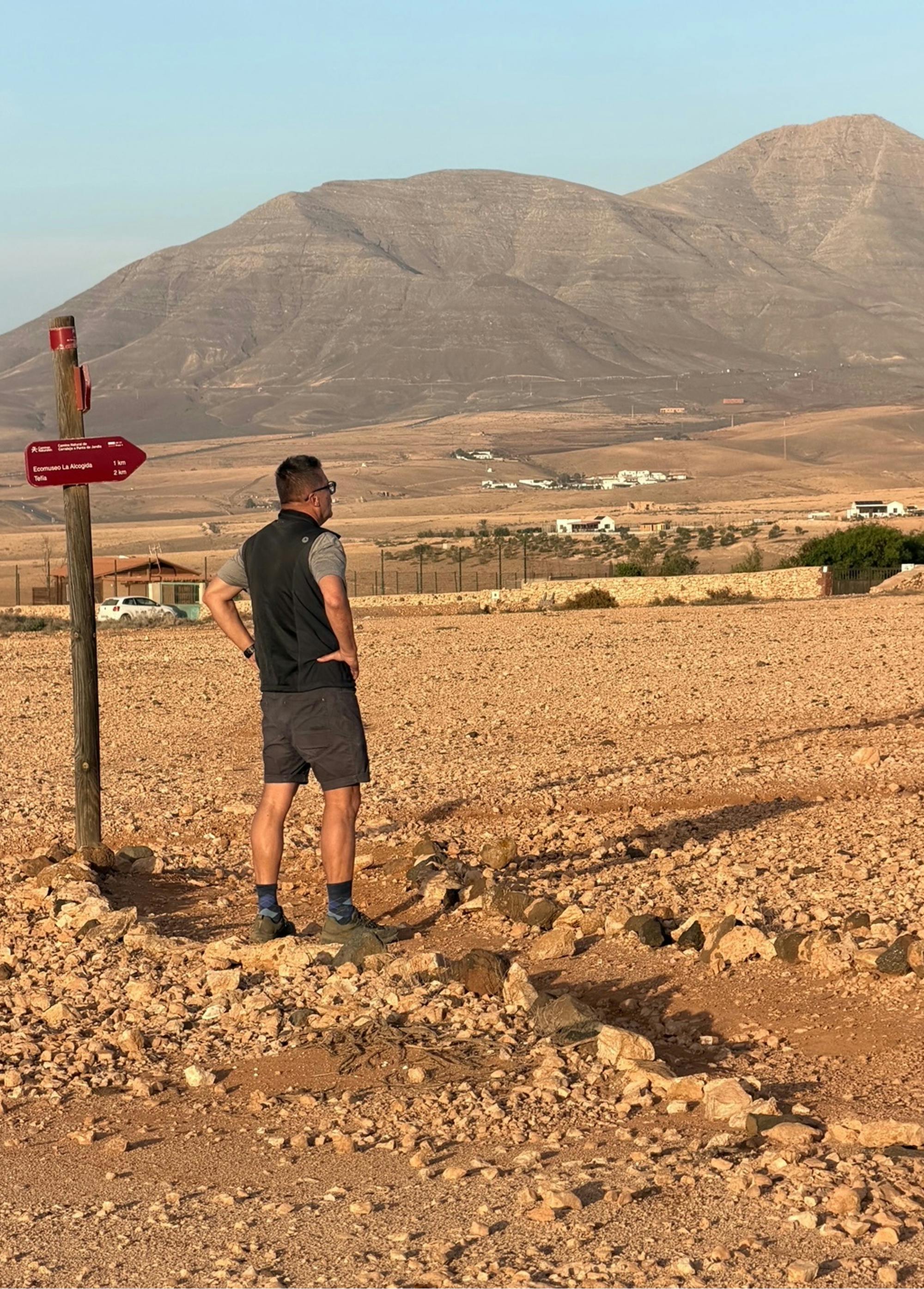 Samo Rugelj med hojo po skalnati ravnini, v ozadju so hribi