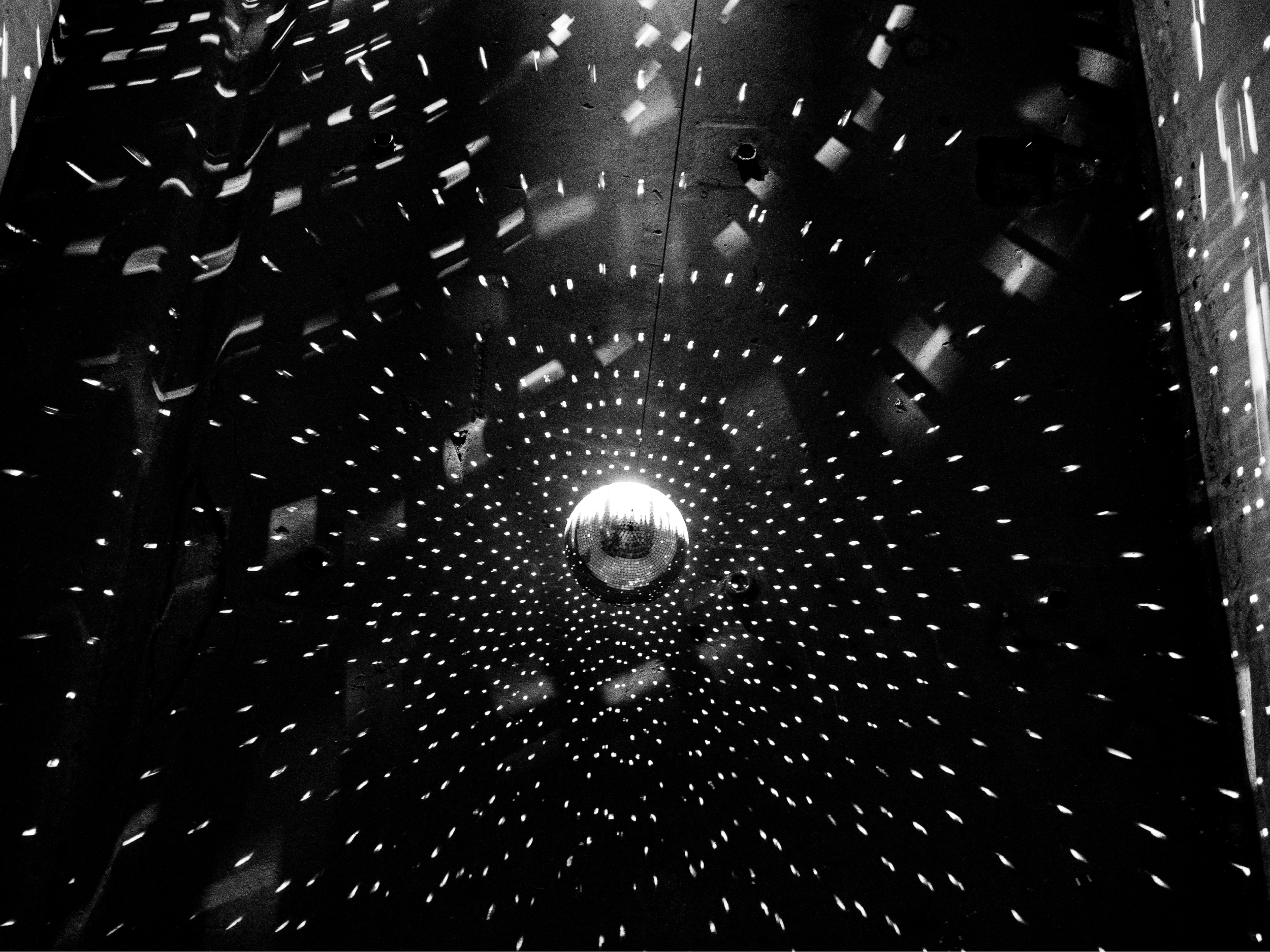 Črno-bela fotografija disko krogle nad plesiščem