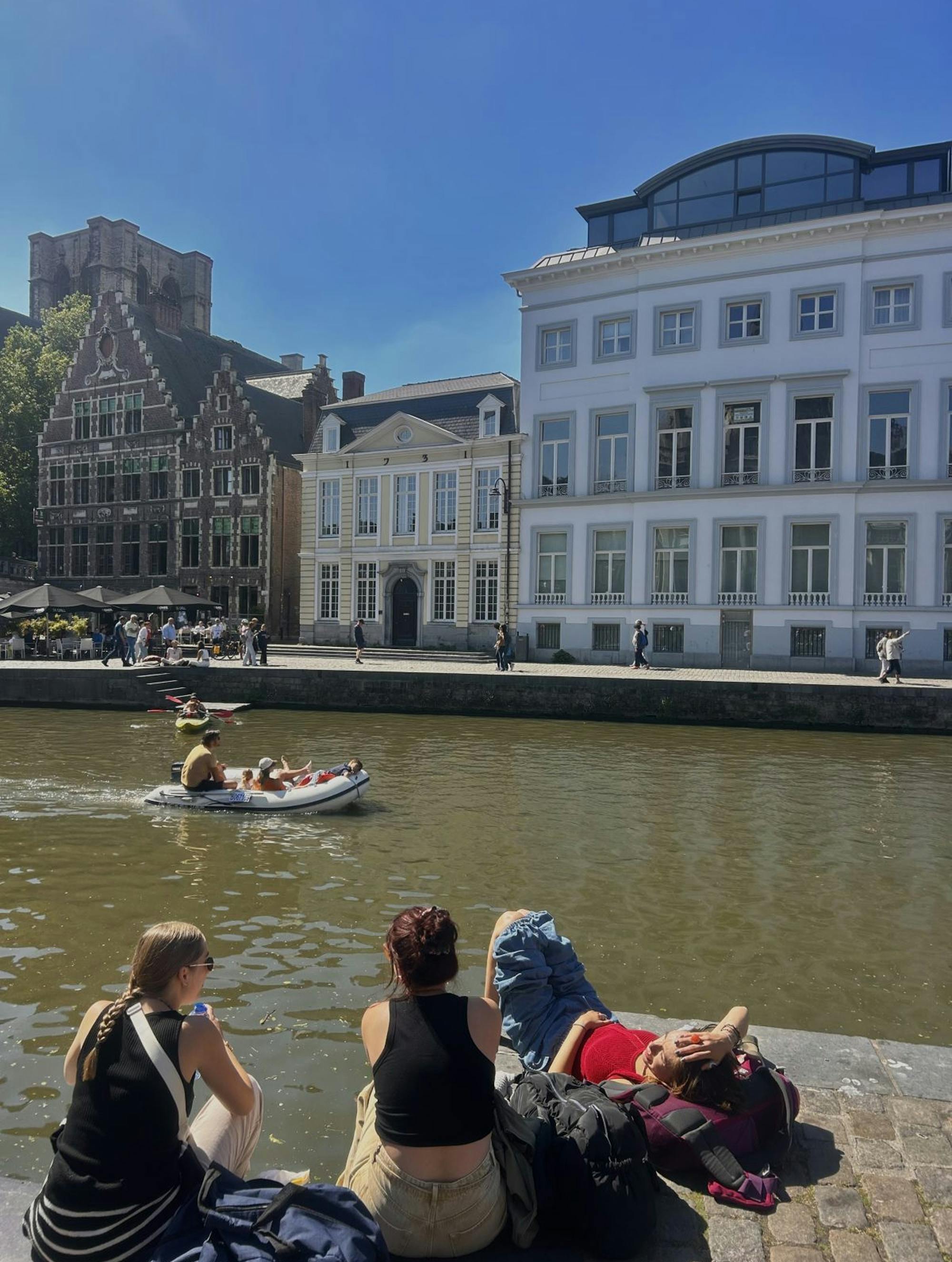 Tri mlada dekleta, ki sedijo pred mestno reko